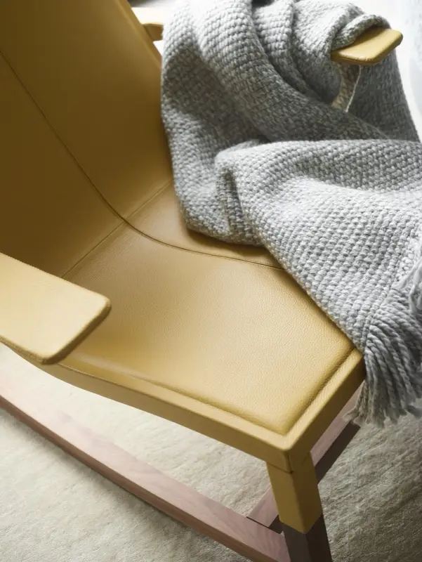 A leather rocking chair with a knitted throw